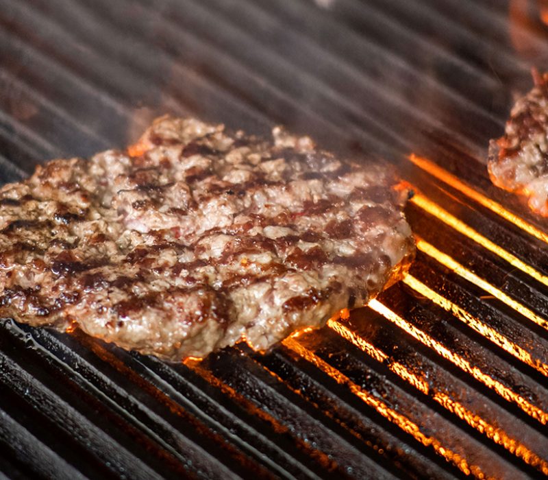 cooking burgers on hot grill with flames